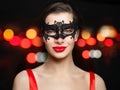 Young smiling woman in carnival mask on abstract red night glitter bokeh background Royalty Free Stock Photo