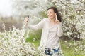 Young smiling woman in casual clothes with earphones listening music doing selfie on mobile phone showing victory sign Royalty Free Stock Photo