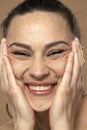 A young smiling woman crumples the skin of her face with her hands