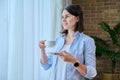 Young smiling woman with cup of morning coffee at home near window Royalty Free Stock Photo