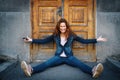 Young woman sitting on ground over old fashioned wooden door