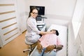 Young smiling woman doctor in diagnostic center making ultrasound thyroid gland test to female African patient. Woman Royalty Free Stock Photo