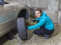 Young smiling woman driver changes car tyres