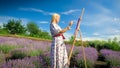 Young smiling woman with easel drawing picture of lavender field