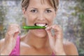 Young blond smiling woman eating green chili pepper standing in front of a table full of vegetable on a old red brick Royalty Free Stock Photo