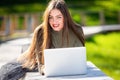 Young elegant woman in eyeglasses lying on bench in park and working on laptop on a sunny and windy day Royalty Free Stock Photo