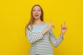 Young smiling woman with fair-haired gestures with hands, pointing fingers right, showing advertisement. Indoor studio shot on