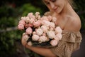 Young smiling woman gently holds bouquet of pastel pink peony flowers in buds Royalty Free Stock Photo