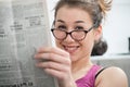 Young and smiling woman with glasses, reading newspaper Royalty Free Stock Photo