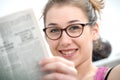 Young and smiling woman with glasses, reading newspaper Royalty Free Stock Photo