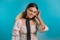 Young smiling woman with hat. Portrait of shy cute beautiful girl in floral dress on blue studio wall background. Royalty Free Stock Photo