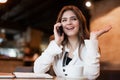 Young smiling woman having phone conversation working outside office during lunch break drinking hot coffee in cafe looking happy Royalty Free Stock Photo