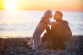 Young smiling woman and her dog playing at sunset beach Royalty Free Stock Photo