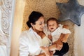 A young smiling woman and her little son are lying on the bedroom floor and having fun. An attractive mom and her sweet baby are Royalty Free Stock Photo