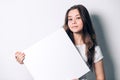 Young smiling woman holding a blank sheet of paper for advertising. Royalty Free Stock Photo