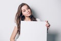 Young smiling woman holding a blank sheet of paper for advertising, close-up Royalty Free Stock Photo