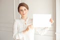 Young smiling woman holding a blank sheet of paper for advertising.Girl showing banner with copy space Royalty Free Stock Photo