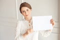 Young smiling woman holding a blank sheet of paper for advertising.Girl showing banner with copy space Royalty Free Stock Photo