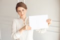 Young smiling woman holding a blank sheet of paper for advertising.Girl showing banner with copy space Royalty Free Stock Photo