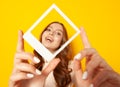 Young smiling woman holding in hands photo frame with her face isolated on yellow background Royalty Free Stock Photo