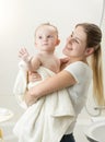 Young smiling woman holding her baby boy covered in towel after bathing Royalty Free Stock Photo