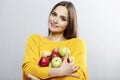 Young smiling woman holding many red and green apples in her hands. Beautiful brunette in a yellow sweater. Healthy food, vitamins Royalty Free Stock Photo