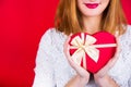 Young smiling woman holding red gift box in shape of heart on re Royalty Free Stock Photo