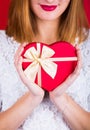 Young smiling woman holding red gift box in shape of heart on re Royalty Free Stock Photo