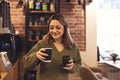 Young smiling woman holding takeaway coffee while standing in coffee shop or cafe Royalty Free Stock Photo
