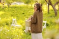 Young smiling woman is holding wicker basket with food in bright nature. Beautiful girl is having picnic in park on Royalty Free Stock Photo