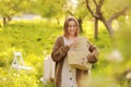 Young smiling woman is holding wicker basket with food in bright nature. Beautiful girl is having picnic in park on Royalty Free Stock Photo