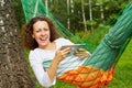 Young smiling woman lies in hammock with tablet PC