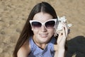 Young smiling woman listens to a seashell Royalty Free Stock Photo