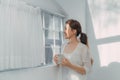 Young smiling woman looking through the window with a cup of drink Royalty Free Stock Photo