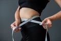 smiling woman measures her ideal waist with a tape measure and shows the result of her diet. Royalty Free Stock Photo