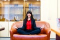 Young smiling woman meditates on the sofa in office