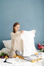 Young woman organizing clothes sitting on the bed at home