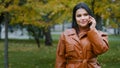 Young smiling woman outdoors in autumn park talking on mobile phone hispanic girl enjoys pleasant conversation Royalty Free Stock Photo