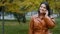 Young smiling woman outdoors in autumn park talking on mobile phone hispanic girl enjoys pleasant conversation Royalty Free Stock Photo
