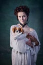 Young smiling woman with pale skin and blushing cheeks holding little dog king charles terrier  over dark green Royalty Free Stock Photo