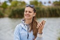 Young smiling woman with a phone listens to music on headphones with close eyes Royalty Free Stock Photo