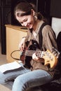 young smiling woman playing bass guitar and reading chord notes at band rehearsal. vertical size Royalty Free Stock Photo