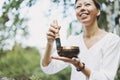 Young smiling woman playing on brass Tibetan singing bowl outdoor. Sound therapy and meditation Royalty Free Stock Photo