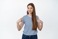 Young smiling woman pointing fingers at herself, self-promoting, standing in casual striped t-shirt over white Royalty Free Stock Photo