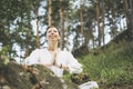Young smiling woman with beads practice yoga outdoors in forest. New normal social distance. Physical and mental health Royalty Free Stock Photo