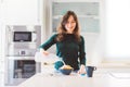 Young smiling woman preparing breakfast, cereal corn flakes with milk and cup of coffee are on the table Royalty Free Stock Photo