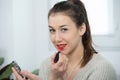 Young and smiling woman putting lipstick Royalty Free Stock Photo