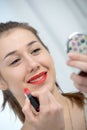 Young and smiling woman putting lipstick Royalty Free Stock Photo