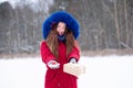 Young smiling woman in red givind gift boxes outdoors