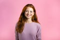 Young smiling woman with red hairstyle looking to camera. Portrait of cute beautiful girl on pink studio wall background Royalty Free Stock Photo